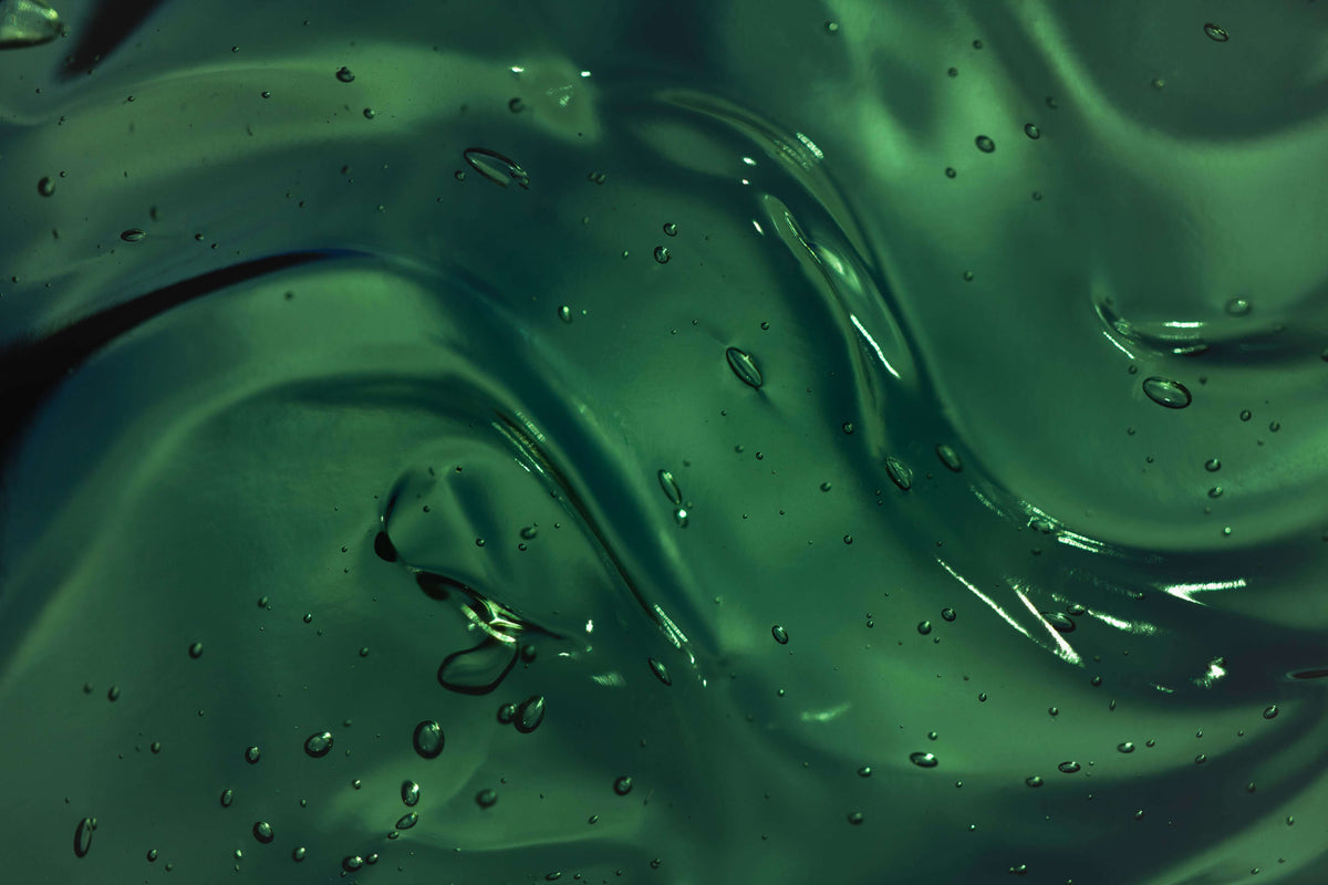 Close-up of green liquid with droplets and reflections
