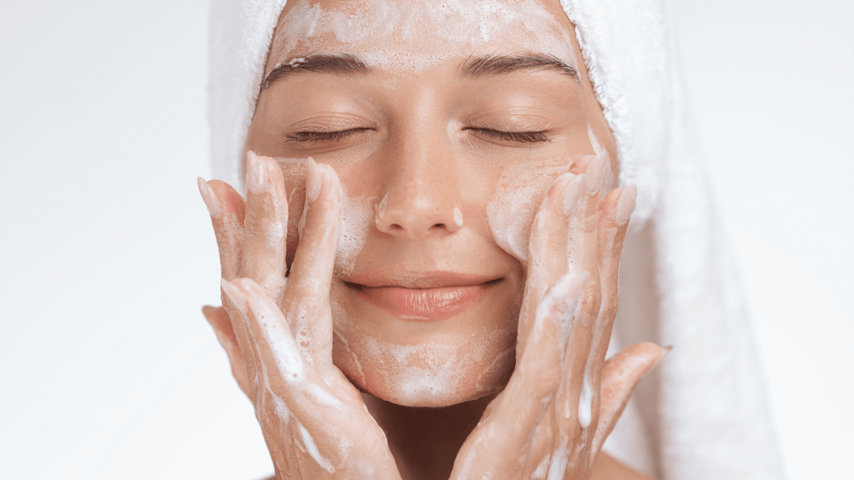 Woman applying a facial mask with a white background