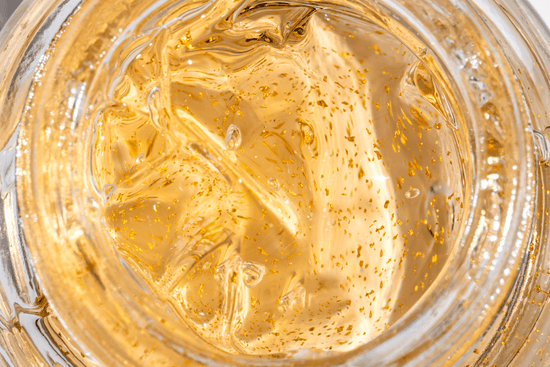 Close-up of a jar filled with gold-colored cream or gel.