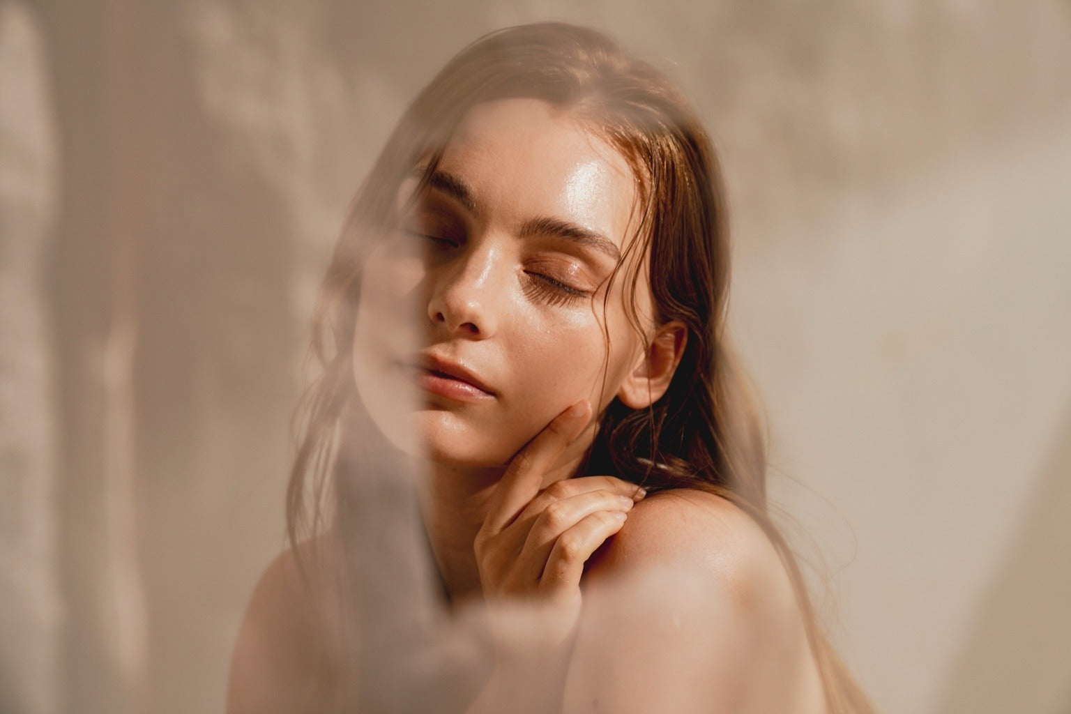 Woman with wet hair looking at herself in a mirror with a soft, warm color tone.