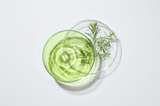 Glass with green liquid and herbs on a white background