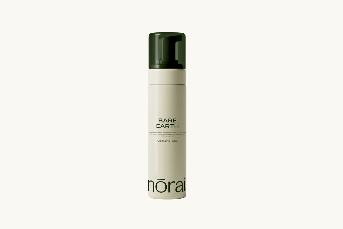 Skincare bottle labeled 'Bare Earth' by 'nora' on a white background