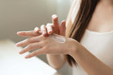Person applying cream to their hand with a neutral background