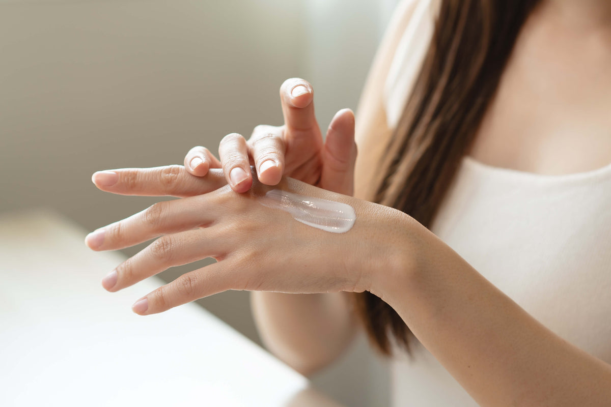 Person applying cream to their hand with a neutral background